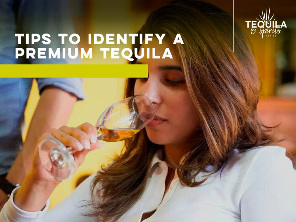 A young woman smelling a glass with tequila to identify a premium tequila. 