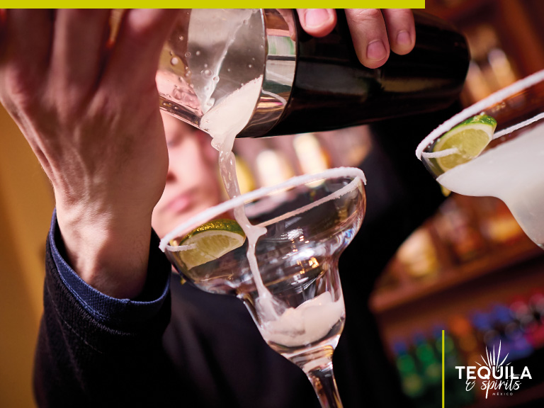 The hands of a bartender are serving a tequila cocktail.