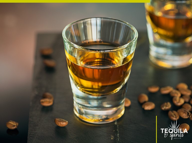 A shot of café-infused tequila with coffee beans in the table.