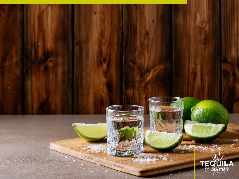 Two silver tequila shots, with salt and lemon slices.