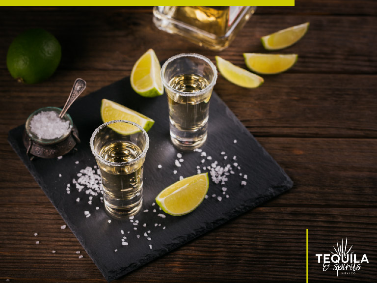 Two shots of tequila reposado. There´s salt around, over a wooden table.
